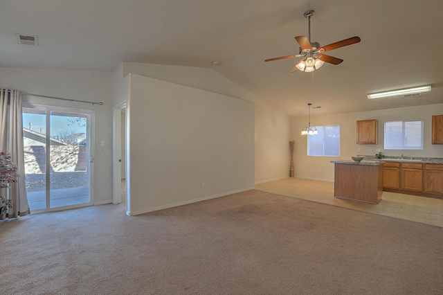 unfurnished living room featuring light colored carpet, vaulted ceiling, sink, and ceiling fan with notable chandelier