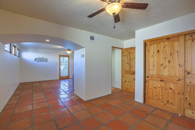 tiled empty room with ceiling fan and a textured ceiling