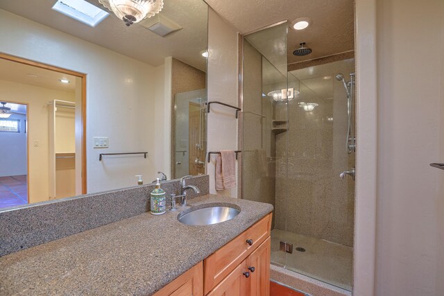 bathroom featuring a shower with door, a skylight, and vanity