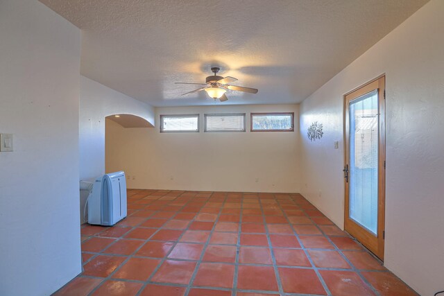 empty room with ceiling fan, a healthy amount of sunlight, and tile patterned flooring