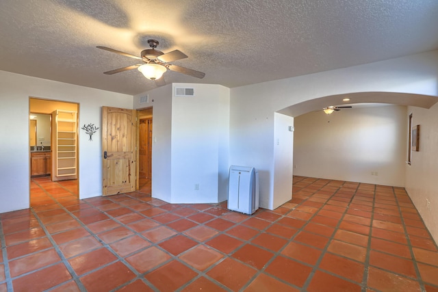 tiled empty room featuring a textured ceiling and ceiling fan