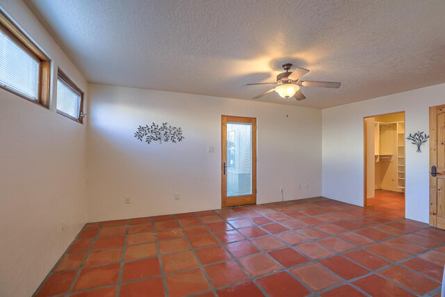 spare room with a textured ceiling, ceiling fan, and tile patterned flooring