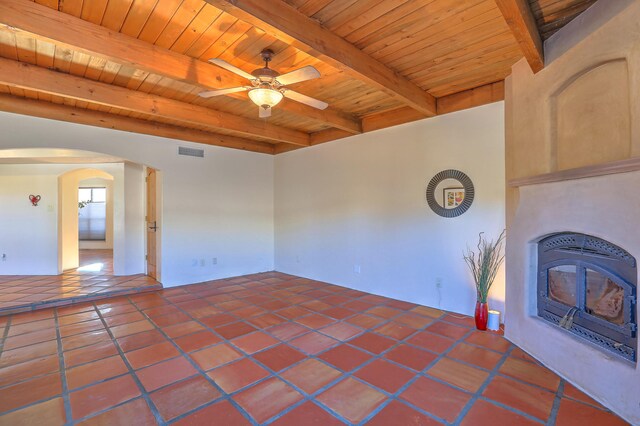 unfurnished living room with wood ceiling, tile patterned floors, a wood stove, ceiling fan, and beam ceiling