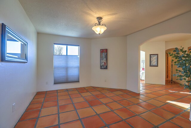 tiled spare room featuring a textured ceiling