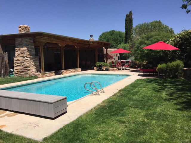 view of pool featuring ceiling fan, an outdoor living space with a fireplace, and a patio area