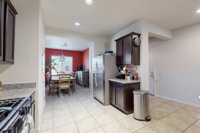 kitchen with decorative light fixtures, light stone countertops, appliances with stainless steel finishes, and dark brown cabinetry