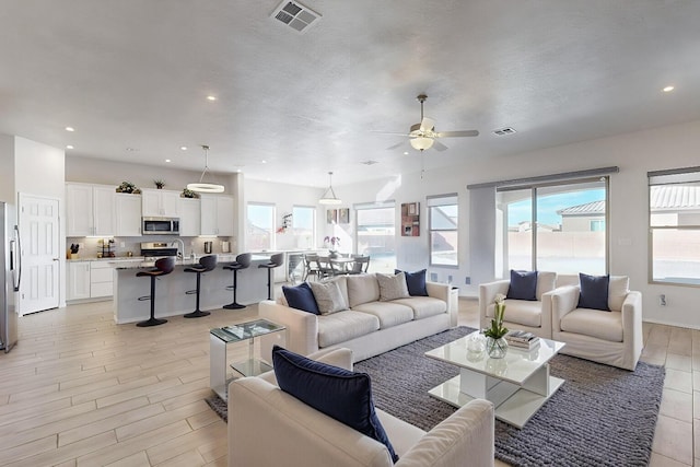 living room with ceiling fan, sink, and a textured ceiling