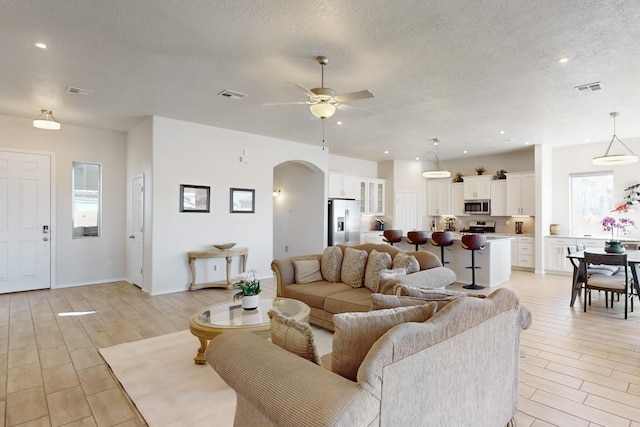 living room with ceiling fan and a textured ceiling