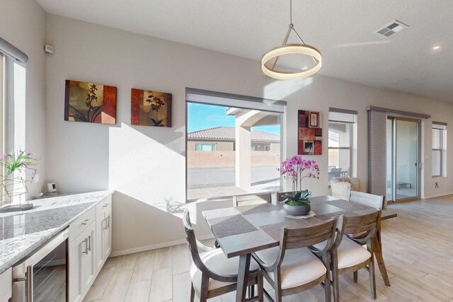 dining room featuring beverage cooler and light hardwood / wood-style flooring