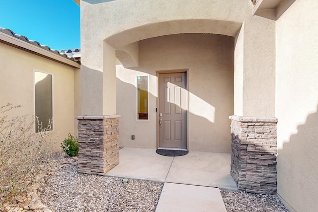 doorway to property with a patio, a tiled roof, and stucco siding