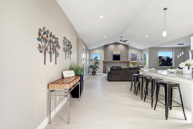 interior space featuring ceiling fan, lofted ceiling, and a fireplace