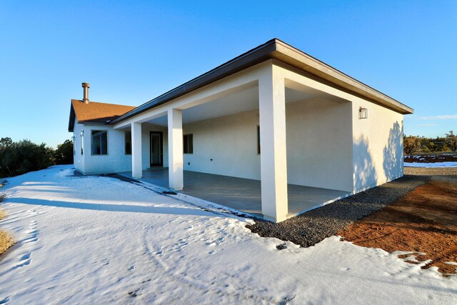 snow covered property with a patio