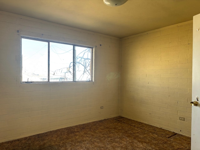 carpeted spare room with brick wall