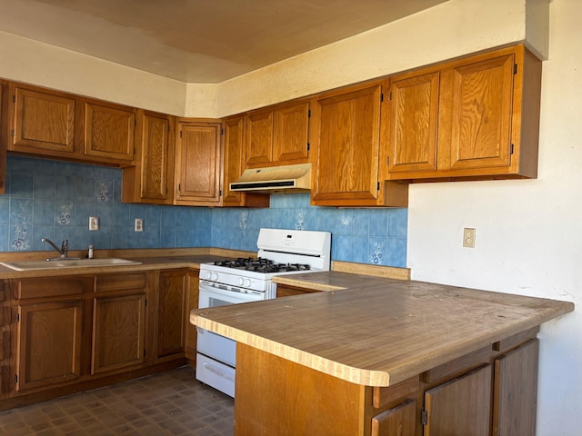 kitchen featuring backsplash, kitchen peninsula, white gas range oven, and sink