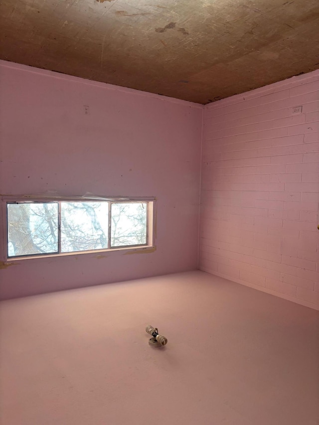 unfurnished room with brick wall and wood ceiling