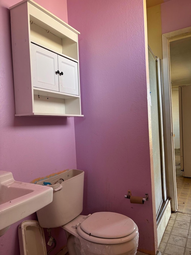 bathroom featuring toilet and a shower with door