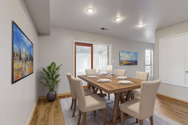 dining room with a textured ceiling and light hardwood / wood-style floors