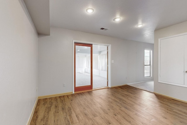 unfurnished room with a textured ceiling and light hardwood / wood-style floors