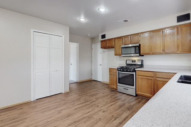 kitchen with appliances with stainless steel finishes, light hardwood / wood-style flooring, and sink