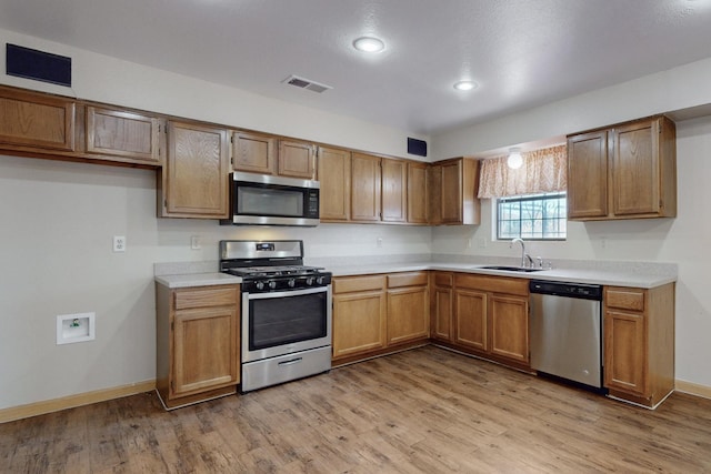 kitchen featuring stainless steel appliances, light hardwood / wood-style floors, and sink