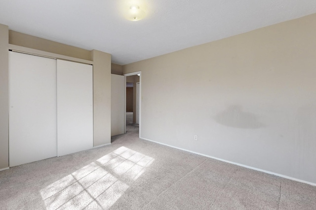 unfurnished bedroom featuring light colored carpet and a closet