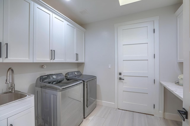 laundry area featuring washing machine and dryer, cabinets, and sink