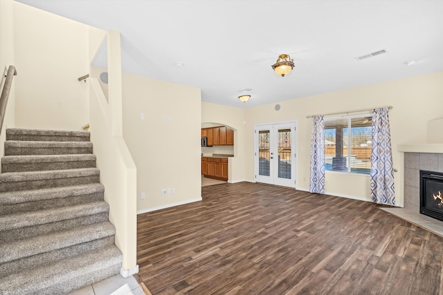 unfurnished living room with hardwood / wood-style flooring, french doors, and a fireplace