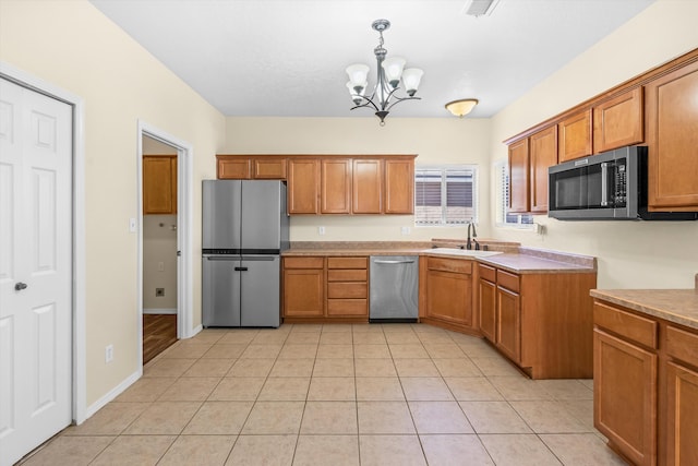 kitchen featuring appliances with stainless steel finishes, an inviting chandelier, sink, hanging light fixtures, and light tile patterned flooring