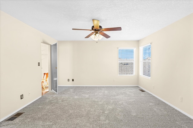 carpeted empty room featuring ceiling fan and a textured ceiling