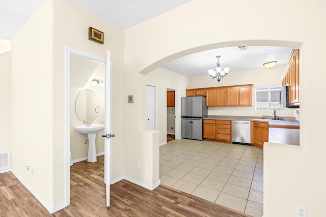 kitchen featuring decorative light fixtures, appliances with stainless steel finishes, sink, and light hardwood / wood-style flooring