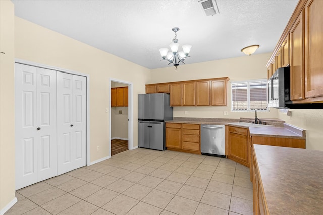 kitchen with decorative light fixtures, sink, stainless steel appliances, light tile patterned floors, and a chandelier