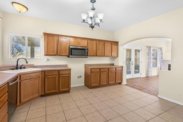 kitchen featuring appliances with stainless steel finishes, decorative light fixtures, french doors, a chandelier, and sink