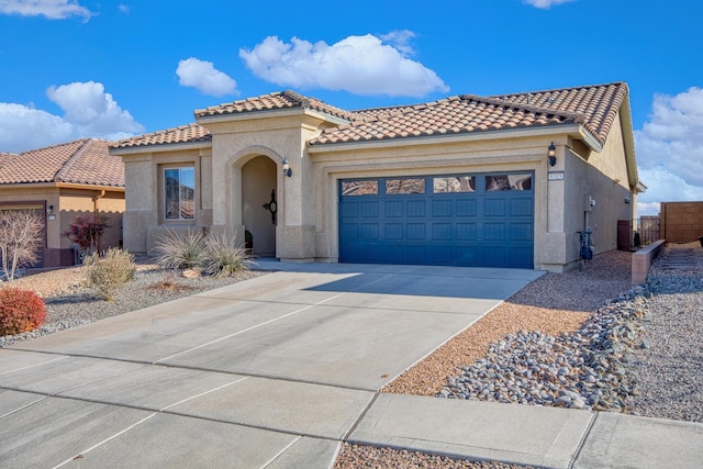 mediterranean / spanish home featuring an attached garage, a tiled roof, concrete driveway, and stucco siding