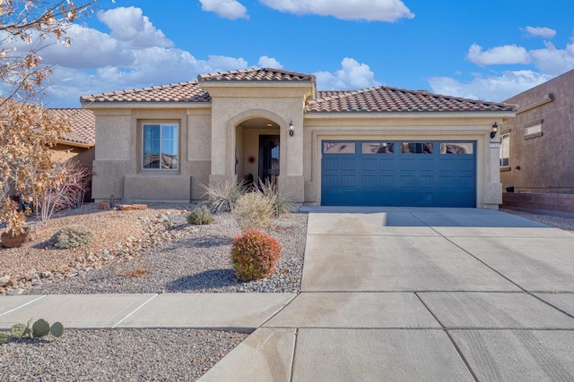 mediterranean / spanish-style house with a garage, concrete driveway, a tiled roof, and stucco siding