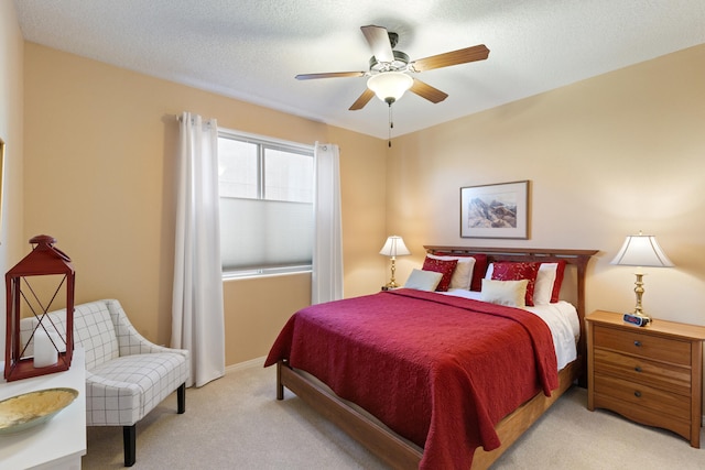 bedroom featuring ceiling fan, light carpet, and a textured ceiling