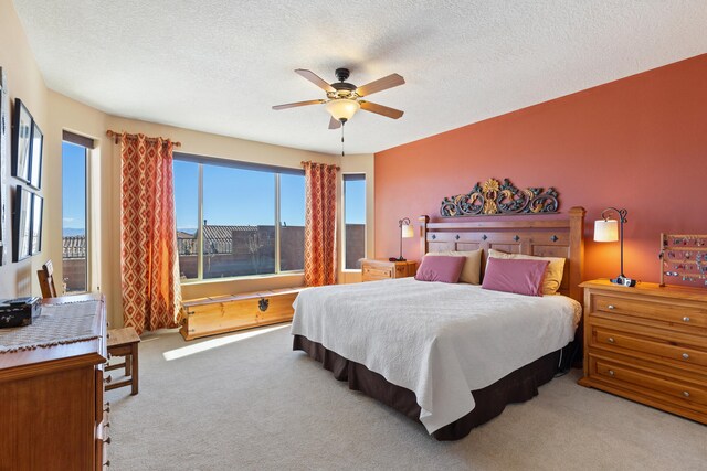 carpeted bedroom featuring ceiling fan and a textured ceiling