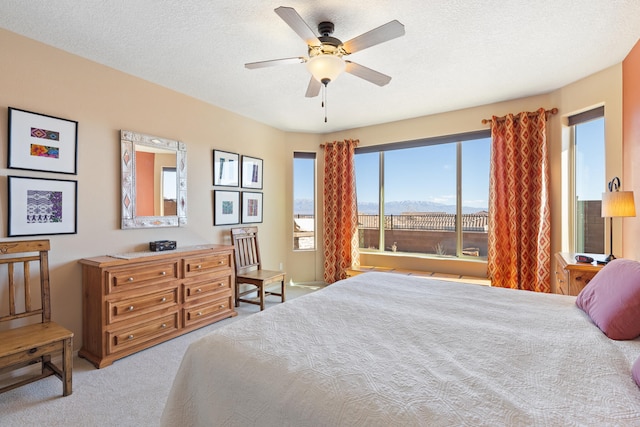 bedroom with carpet floors, ceiling fan, and a textured ceiling