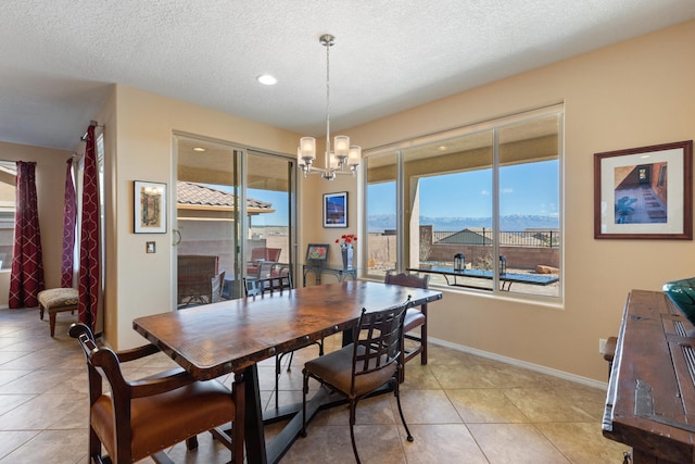 dining room with a mountain view, a textured ceiling, light tile patterned floors, and a chandelier