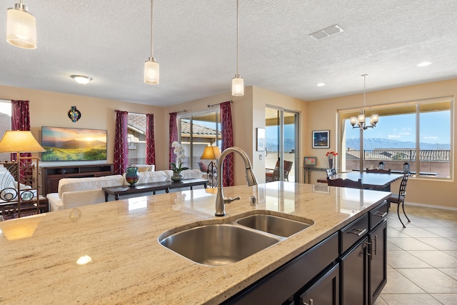 kitchen featuring light stone countertops, sink, a textured ceiling, and pendant lighting