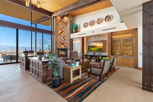 living area with a large fireplace, visible vents, wooden ceiling, a wall of windows, and track lighting