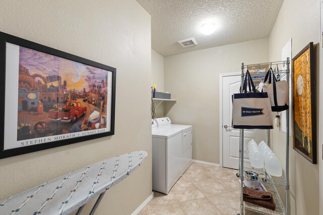 clothes washing area with a textured ceiling, light tile patterned floors, and independent washer and dryer