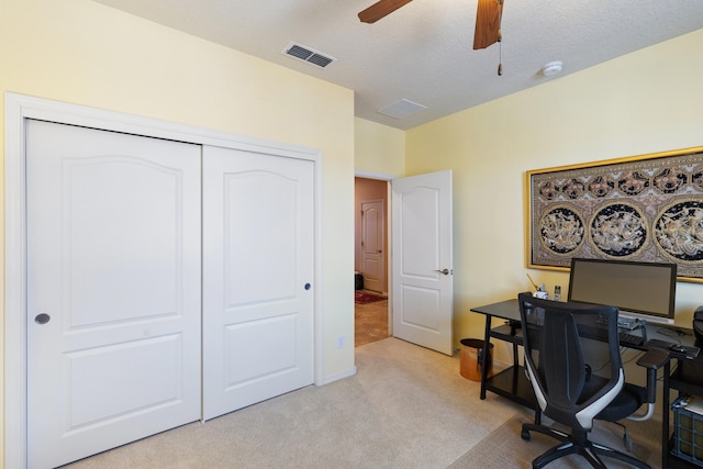 office featuring visible vents, ceiling fan, light carpet, and a textured ceiling