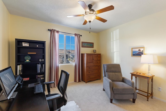 office space featuring light carpet, ceiling fan, and a textured ceiling