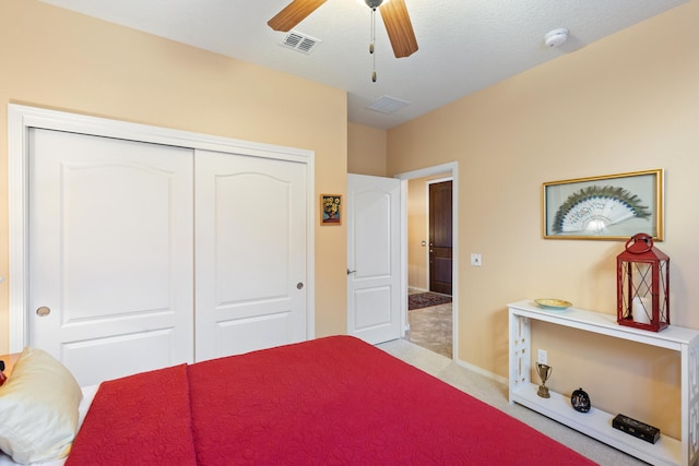 bedroom with a closet, visible vents, a ceiling fan, light carpet, and a textured ceiling