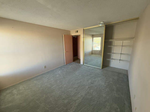 unfurnished bedroom with a textured ceiling, a closet, and dark carpet