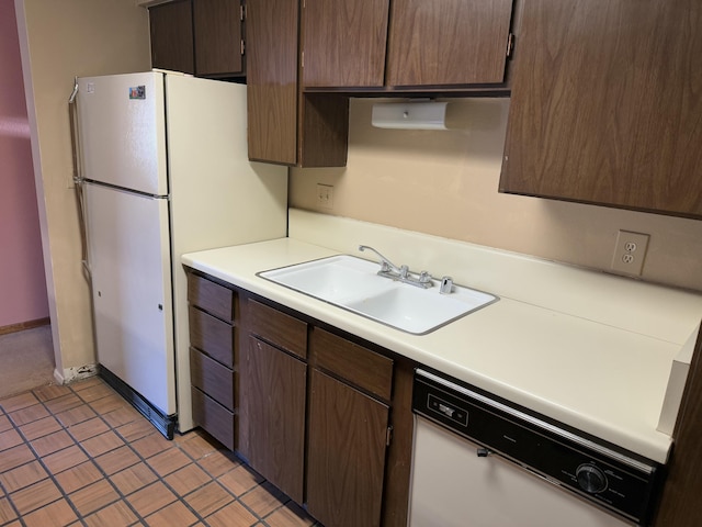 kitchen with light tile patterned floors, dark brown cabinets, sink, and white appliances