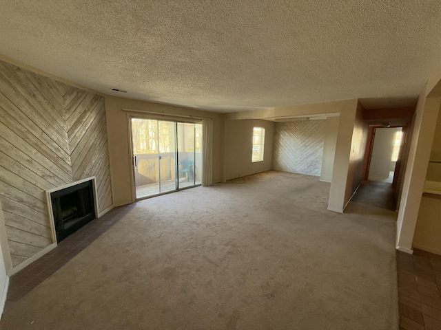 unfurnished living room featuring carpet floors, a textured ceiling, and wooden walls