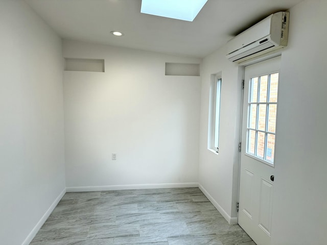 unfurnished room featuring a skylight and a wall unit AC