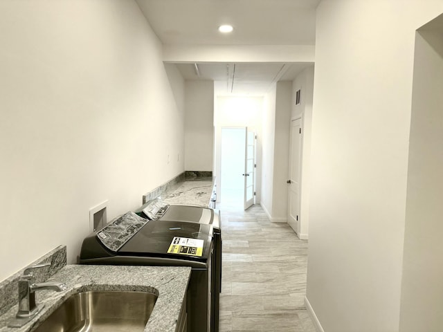 kitchen featuring light stone counters, sink, and washer and dryer