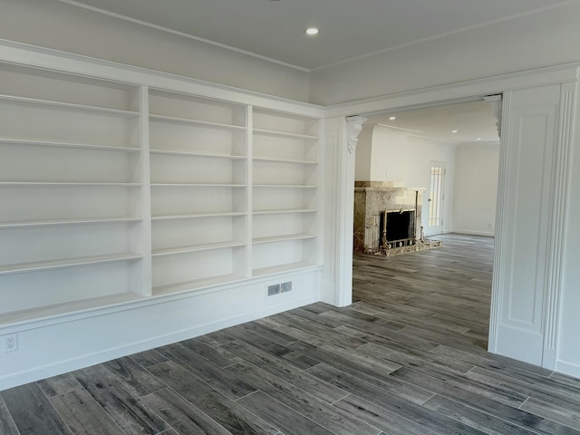 unfurnished living room with built in shelves, decorative columns, and hardwood / wood-style flooring